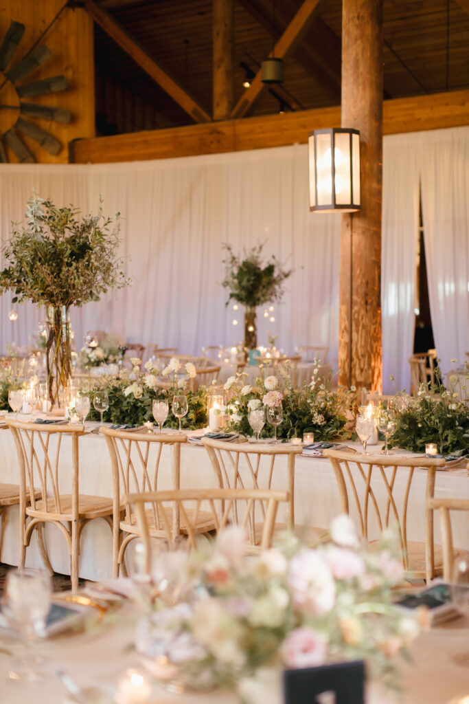 Saddleridge at Beaver Creek Resort is decorated for a wedding reception with white and pink flowers, tall floral sculptures and white curtains draping in the background.