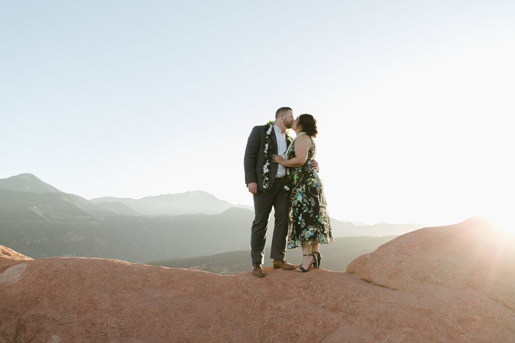 Couple kisses in front of layered peaks at Garden of the Gods in Colorado Springs, Colorado.