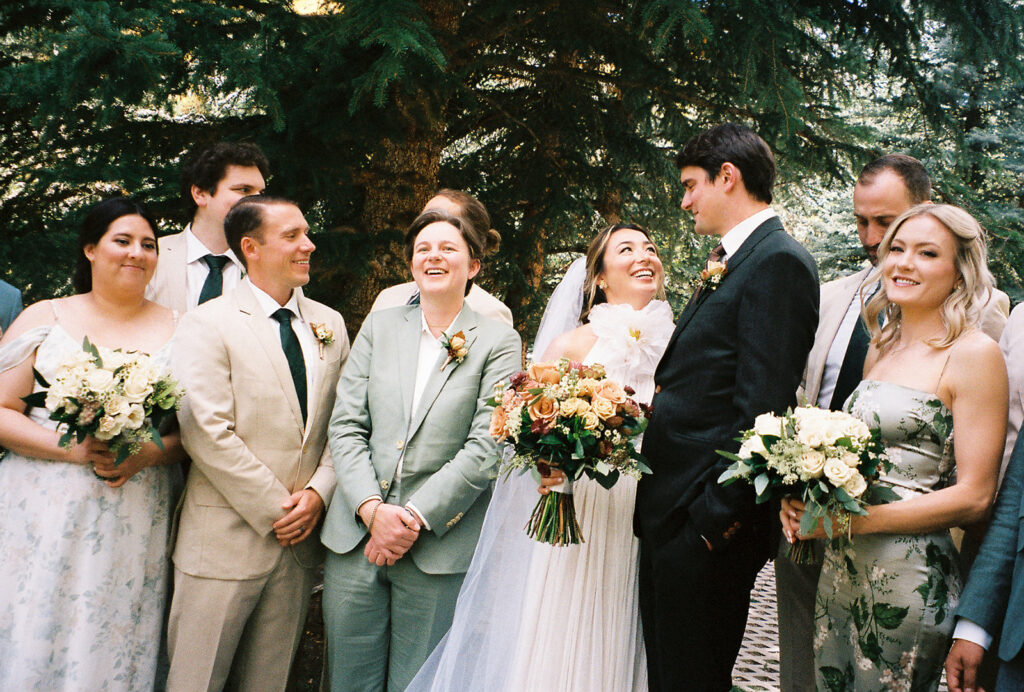 Bride and groom smile at each other alongside wedding party at Sonnenalp Vail. Shot by Jordan Katz.