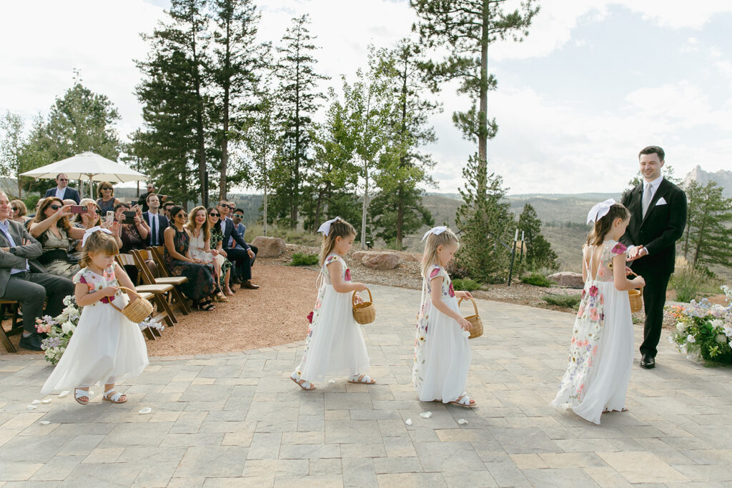 Flower girls walk into ceremony at Pikes Peak Ranch in Woodland Park, Colorado.