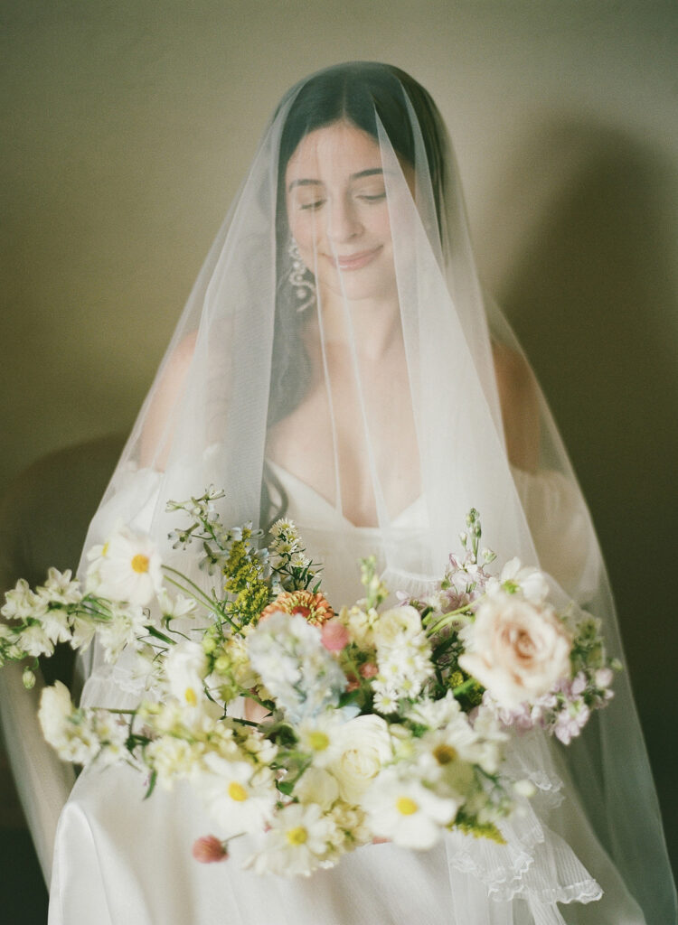 Bride sits with veil and flowers in getting ready suite at Pikes Peak Ranch in Woodland Park, Colorado.